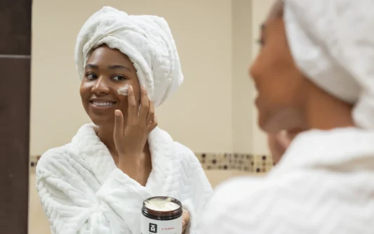 Woman with a towel on her head applying cream