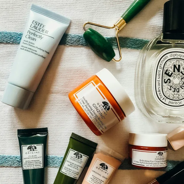 Face care products and a jade roller on a towel