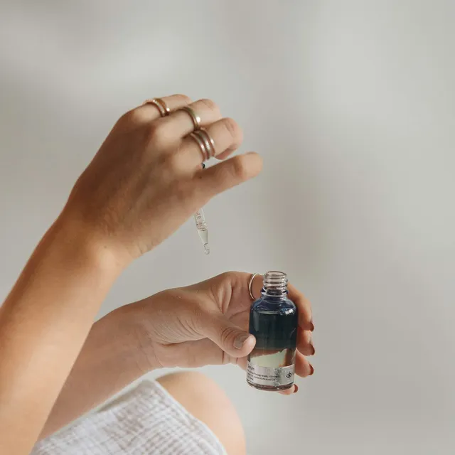 Hands holding a serum dropper bottle